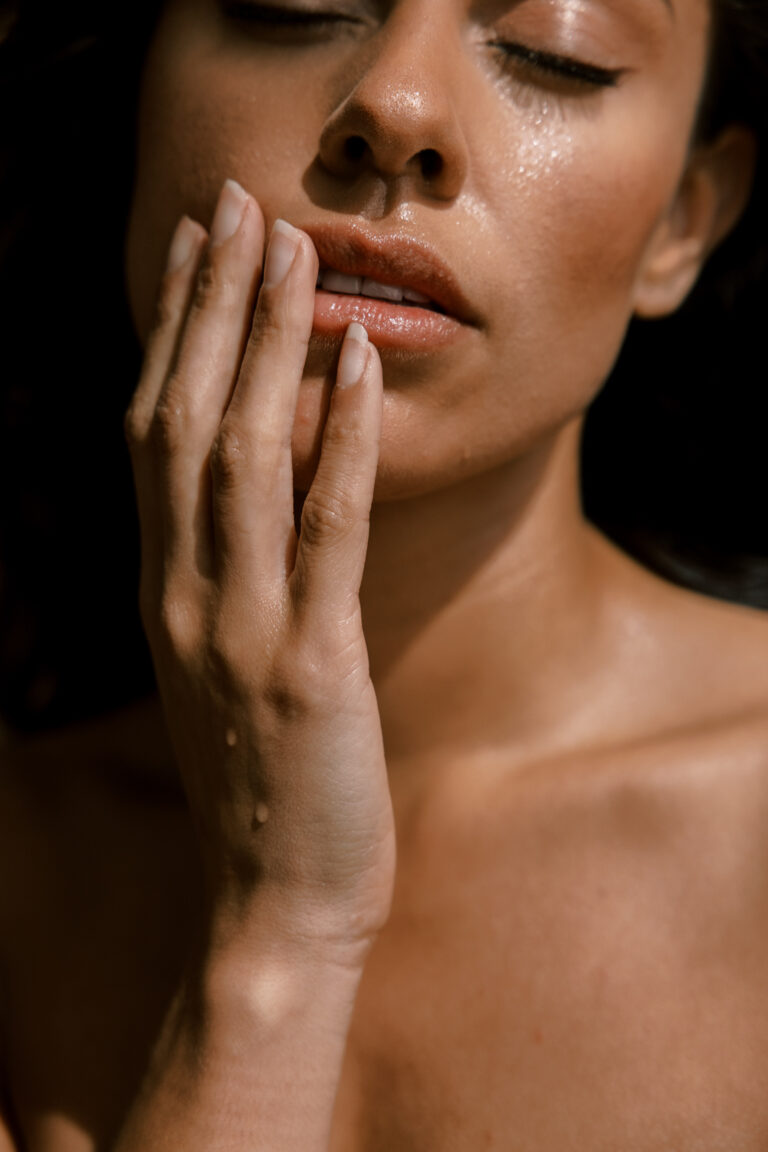 Beautiful woman with radiant brown skin holding hand to face