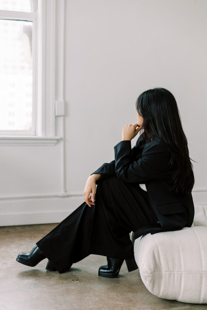 Side profile of woman with dark hair dressing in black suit