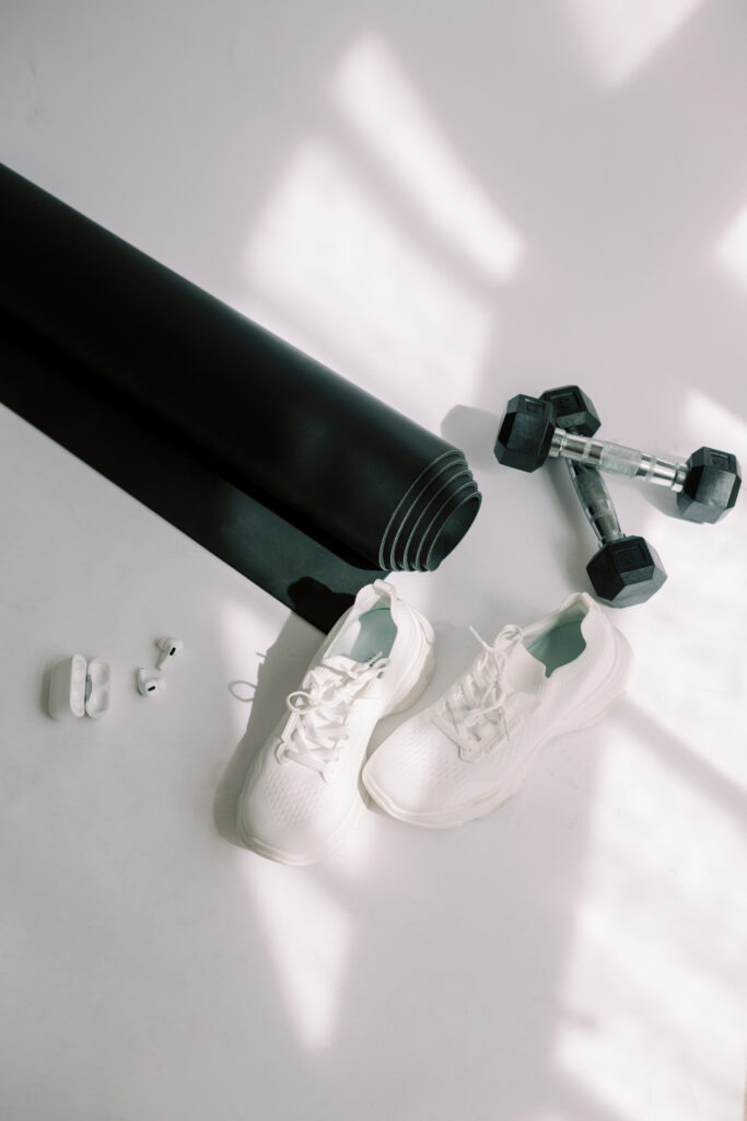 Flat lay of workout gear including mat, weights, sneakers