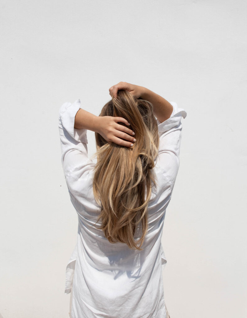 Young blonde woman running hands through hair wearing white shirt